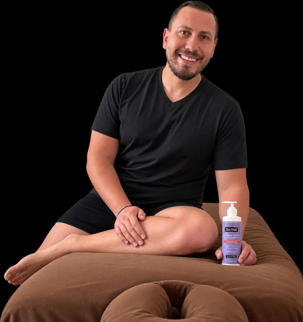 Shawn Wilson, owner of Prism OC Massage, seated on his massage table